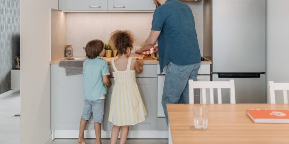 Father and children cooking together in a modern kitchen, enjoying family time.